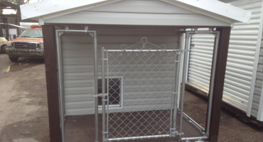 A dog house with a chain link fence and a door.