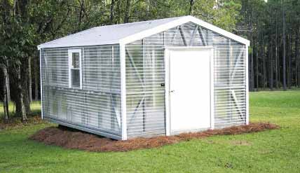 A white shed with a door open and the outside of it.