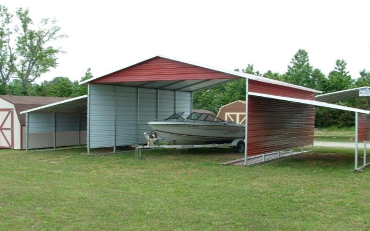 A boat is parked in the shade of a shed.