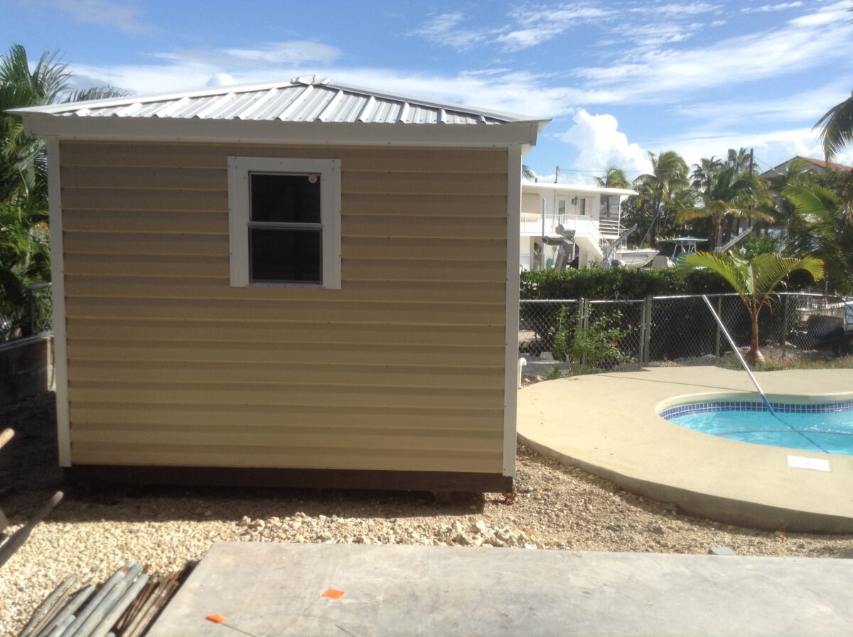 A shed with a metal roof and a pool in the background.