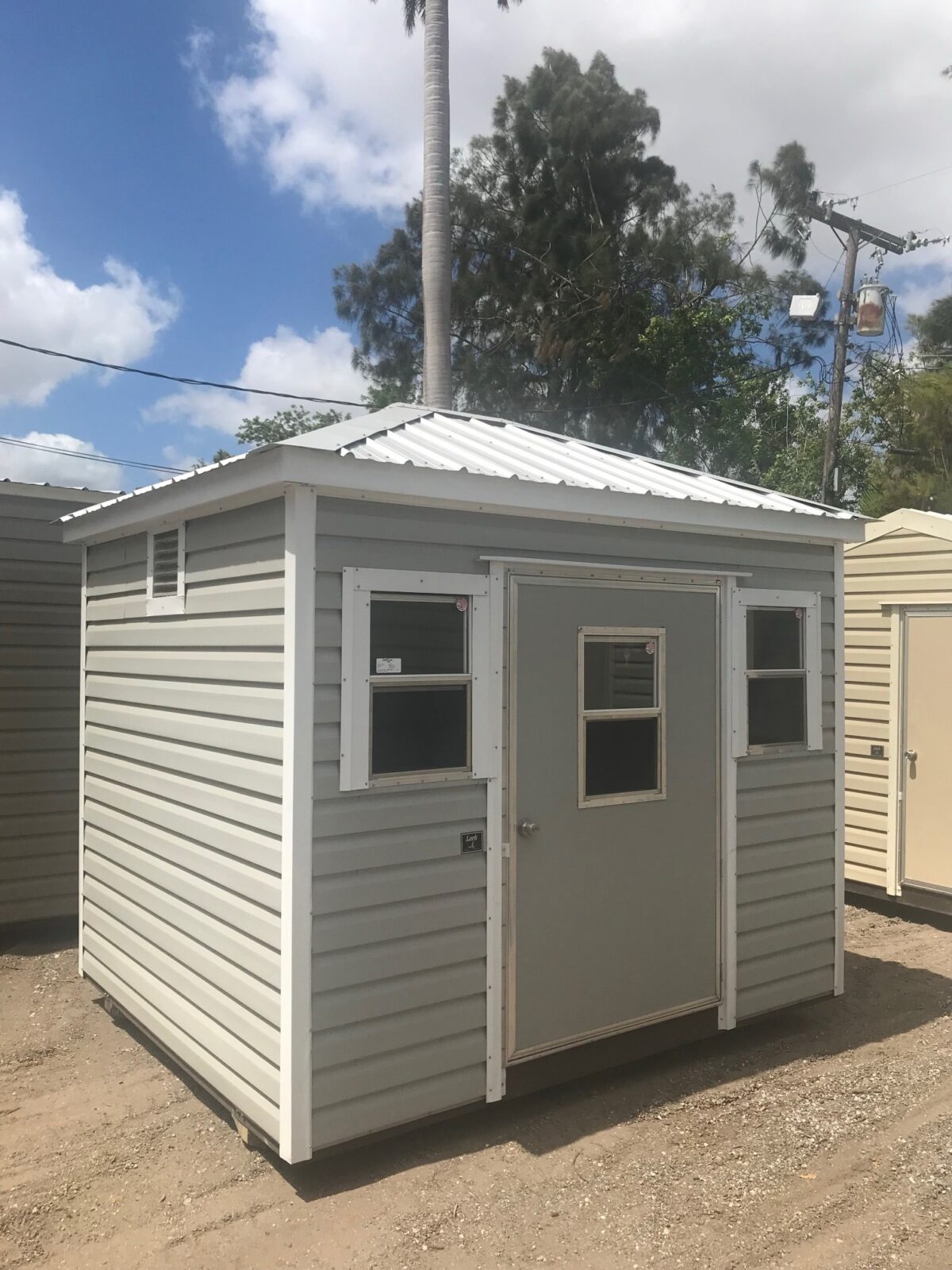 A small white shed sitting in the middle of a lot.